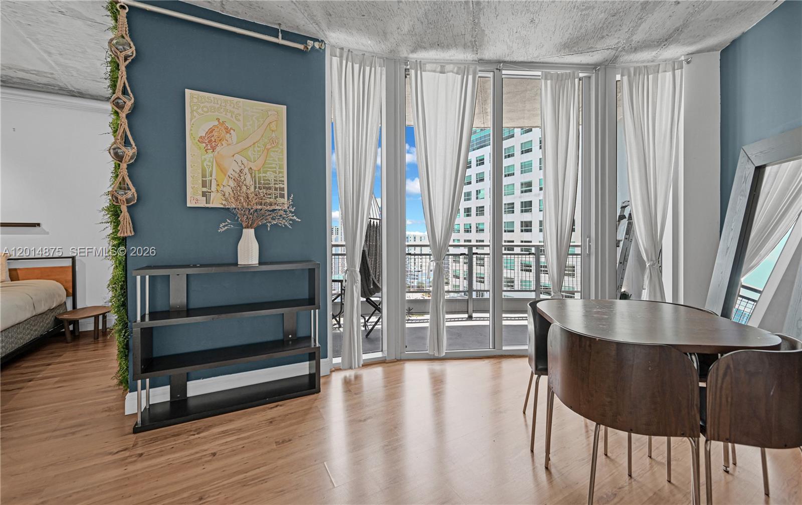 A dining area with wood floors, blue accent wall, and floor-to-ceiling windows leading to a balcony — 690 SW 1st Ct # 1934, Miami FL 33130, MIAMI, FL