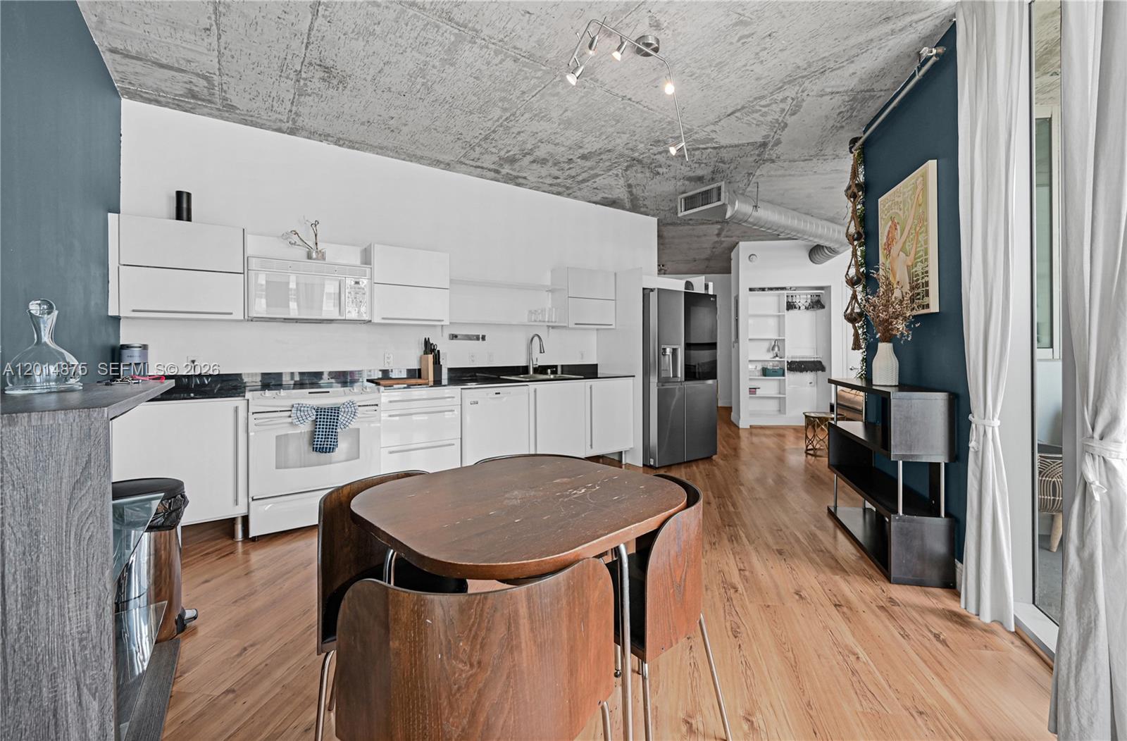 A kitchen and dining area features white cabinetry, a concrete ceiling, and wood flooring — 690 SW 1st Ct # 1934, Miami FL 33130, MIAMI, FL