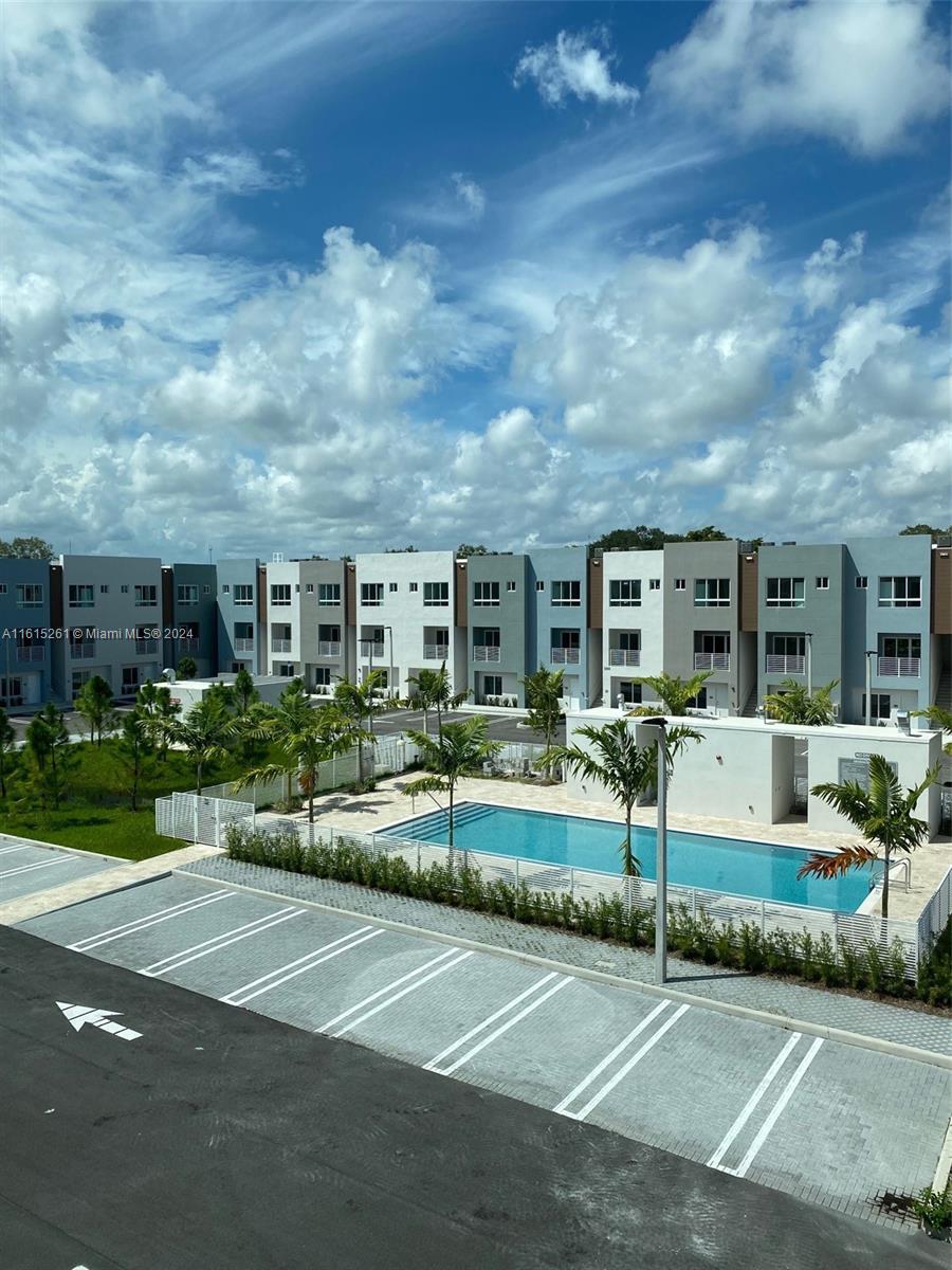 An outdoor swimming pool is situated in front of a row of modern townhouses — 2505 NE 193rd St # 4207, Miami FL 33180, MIAMI, FL