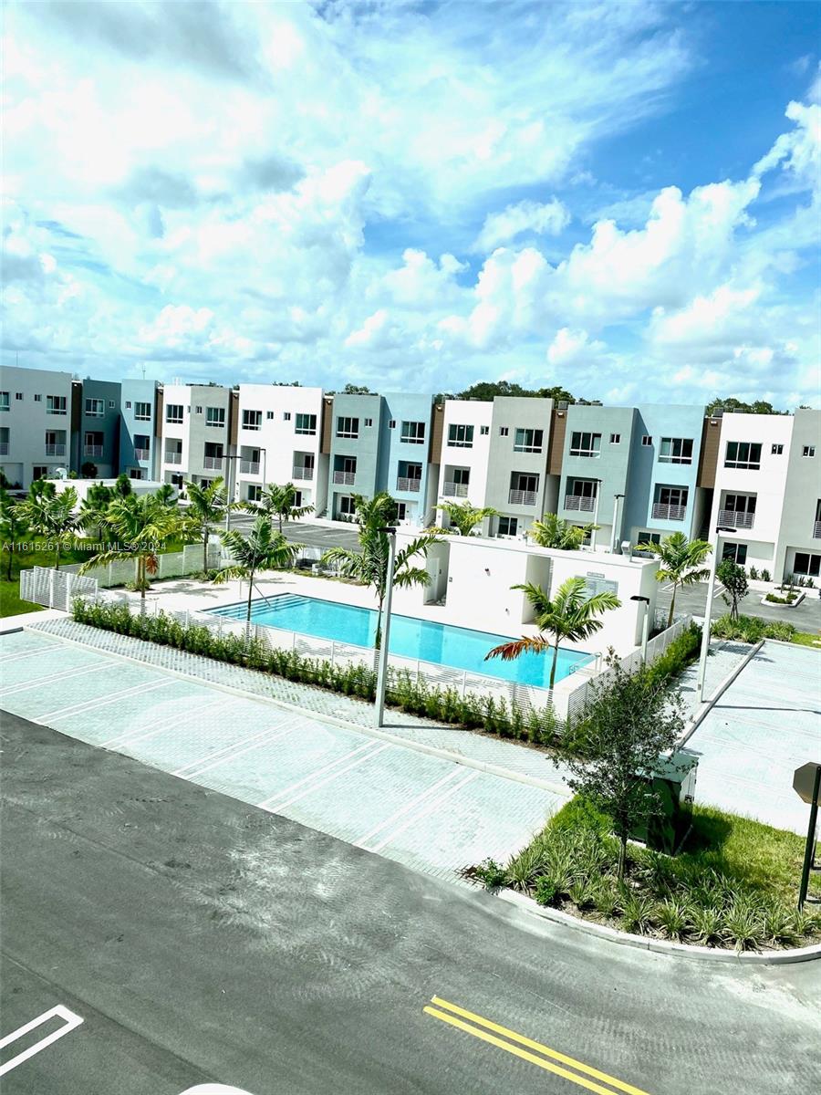 An outdoor swimming pool is situated in front of a modern multi-story apartment complex — 2505 NE 193rd St # 4207, Miami FL 33180, MIAMI, FL