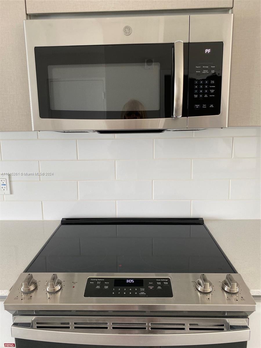 A stainless steel microwave is mounted above a black glass-top electric range in a kitchen — 2505 NE 193rd St # 4207, Miami FL 33180, MIAMI, FL