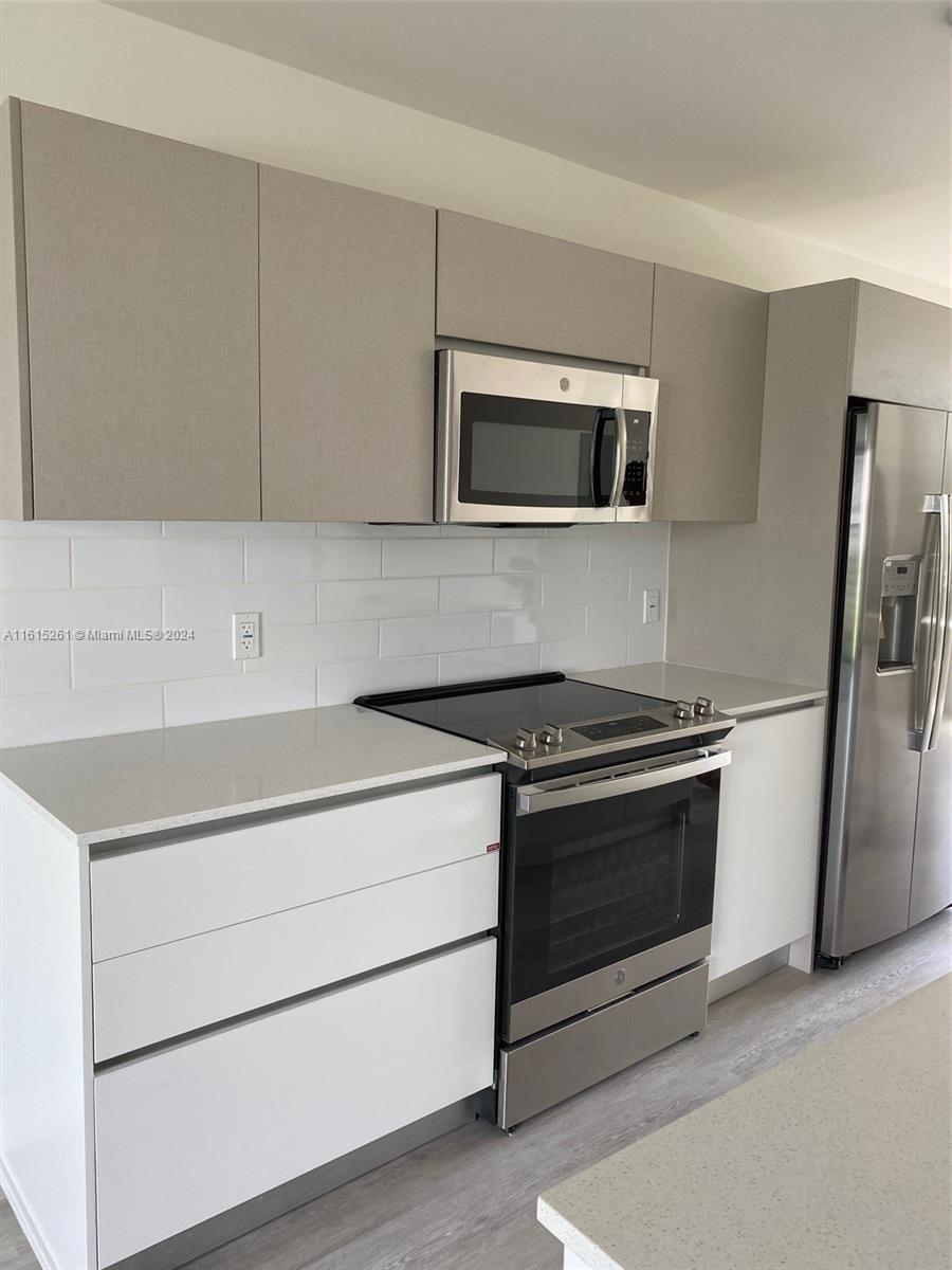 A modern kitchen features white cabinets, stainless steel appliances, and a white subway tile backsplash — 2505 NE 193rd St # 4207, Miami FL 33180, MIAMI, FL