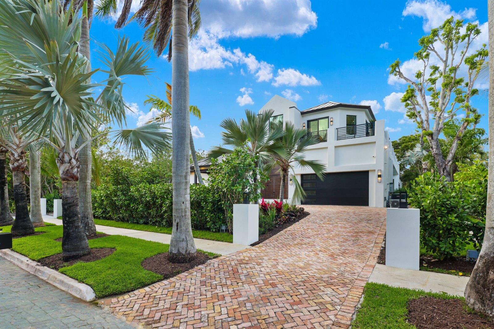 A two-story white modern house features a brick driveway, palm trees, and a black garage — 23 Coconut Lane, Ocean Ridge FL 33435, OCEAN RIDGE, FL