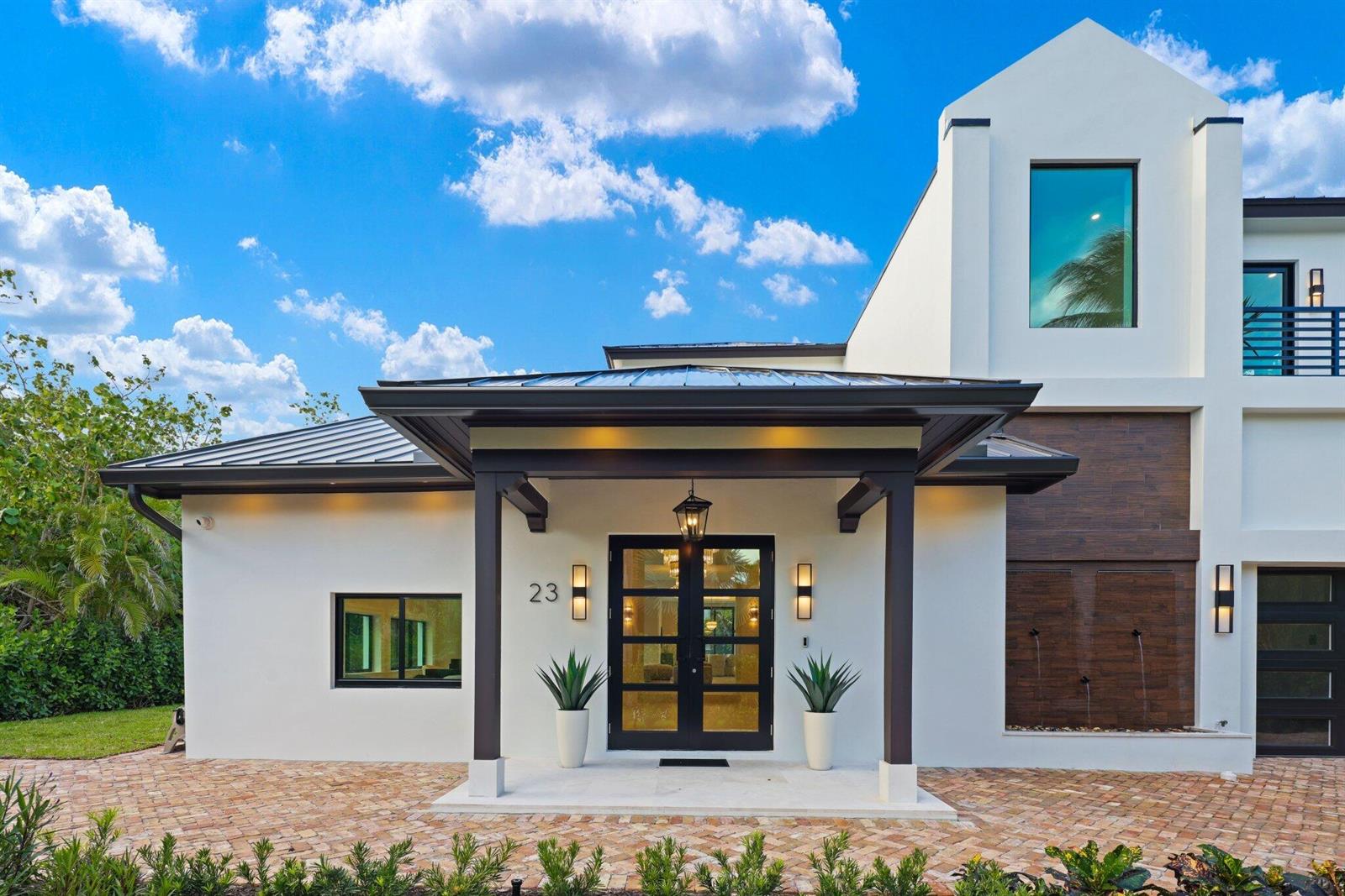 A modern house exterior features a white facade, dark wood accents, and a covered entryway — 23 Coconut Lane, Ocean Ridge FL 33435, OCEAN RIDGE, FL
