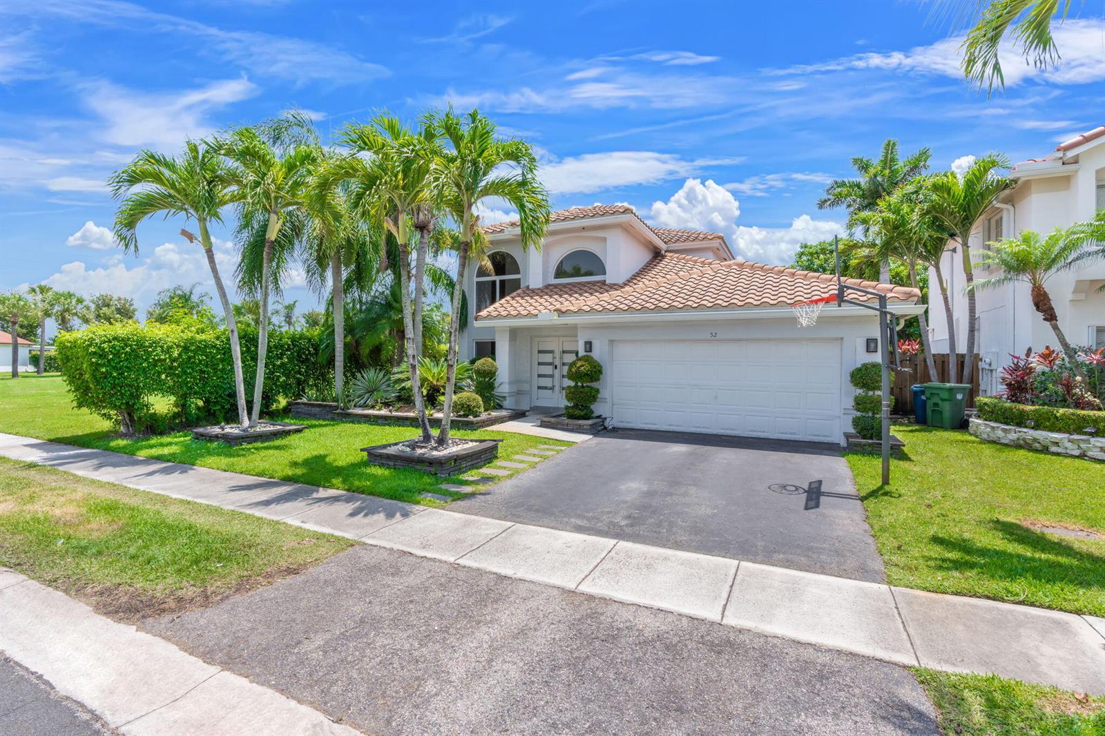 A two-story house with a tile roof, a two-car garage, and palm trees in front — 52 Gables Boulevard, Weston FL 33326, WESTON, FL