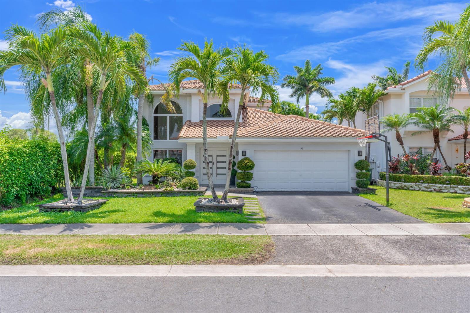 A two-story house with a tile roof, white garage, and palm trees in the front yard — 52 Gables Boulevard, Weston FL 33326, WESTON, FL