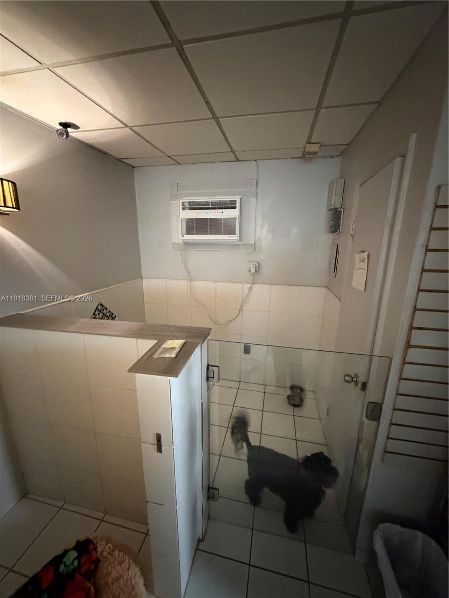 A small tiled room features a glass-enclosed area, a window air conditioner, and a dog — SW Bird road, Miami FL 33155, MIAMI, FL