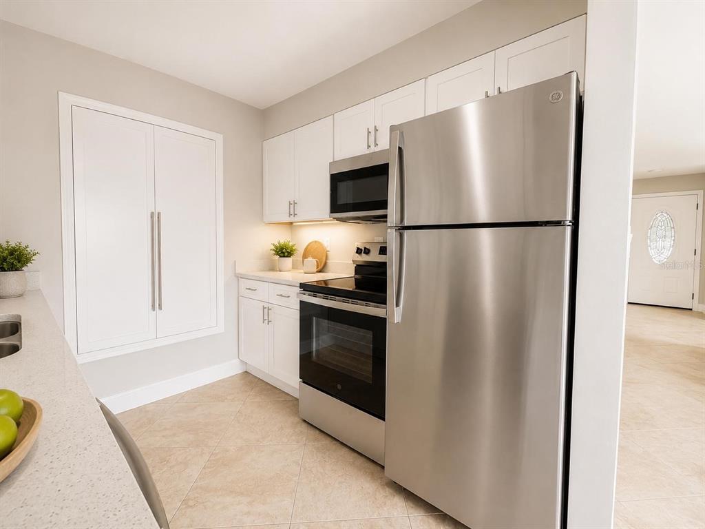 A kitchen features stainless steel appliances, white cabinetry, and light-colored tile flooring — 13326 LARAWAY DRIVE, RIVERVIEW, FL