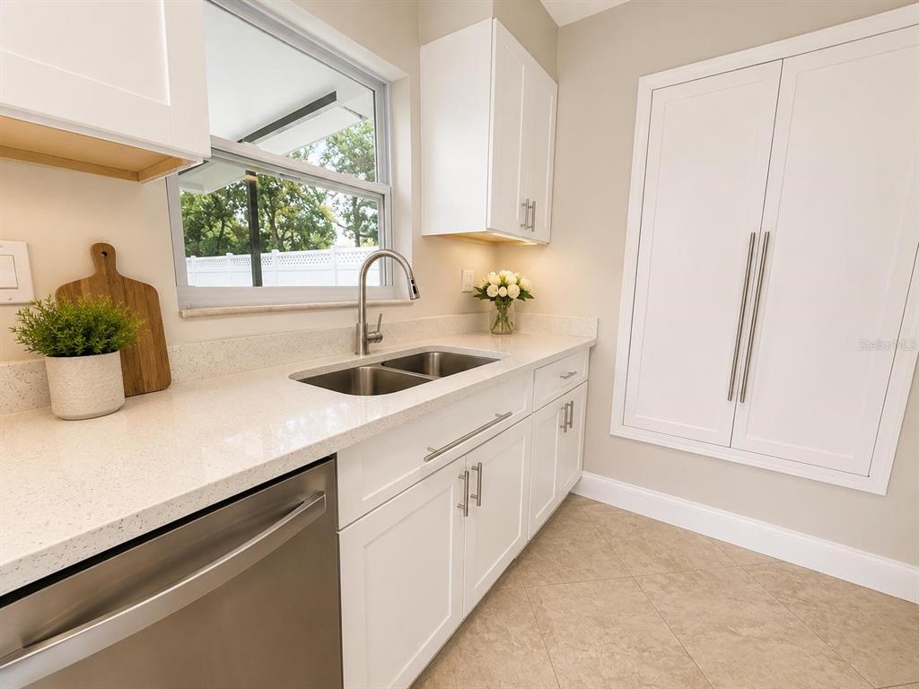 A kitchen features white cabinets, a stainless steel sink, and light-colored countertops — 13326 LARAWAY DRIVE, RIVERVIEW, FL