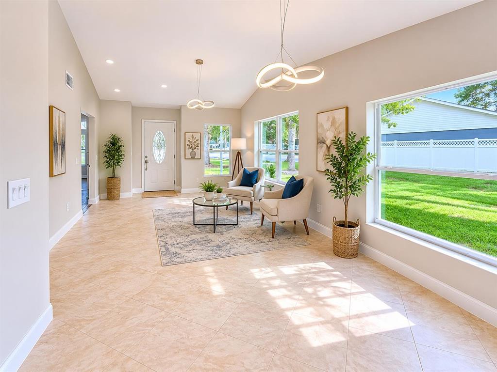 A bright living room features tile floors, two armchairs, a coffee table, and large windows — 13326 LARAWAY DRIVE, RIVERVIEW, FL