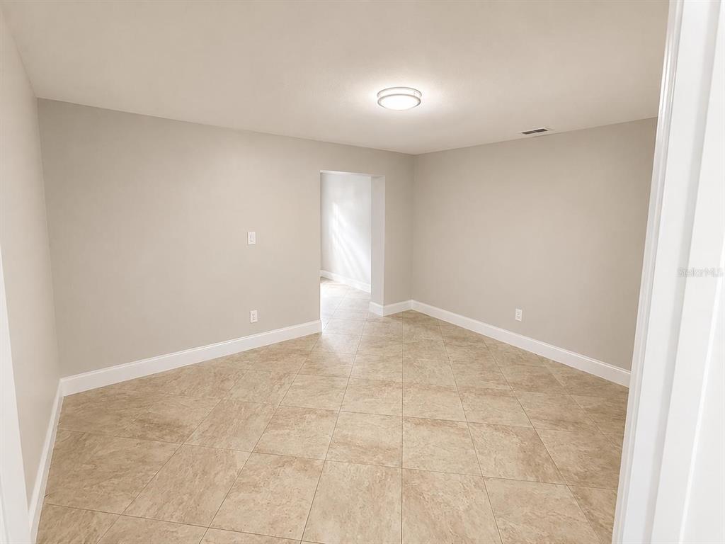 An empty room with light-colored walls, beige tile flooring, and a central ceiling light — 13326 LARAWAY DRIVE, RIVERVIEW, FL