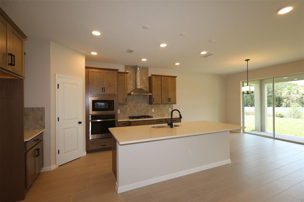 A kitchen with wood cabinets, a large island, stainless appliances, and tile flooring — 1314 HYDE STREET, ST CLOUD, FL