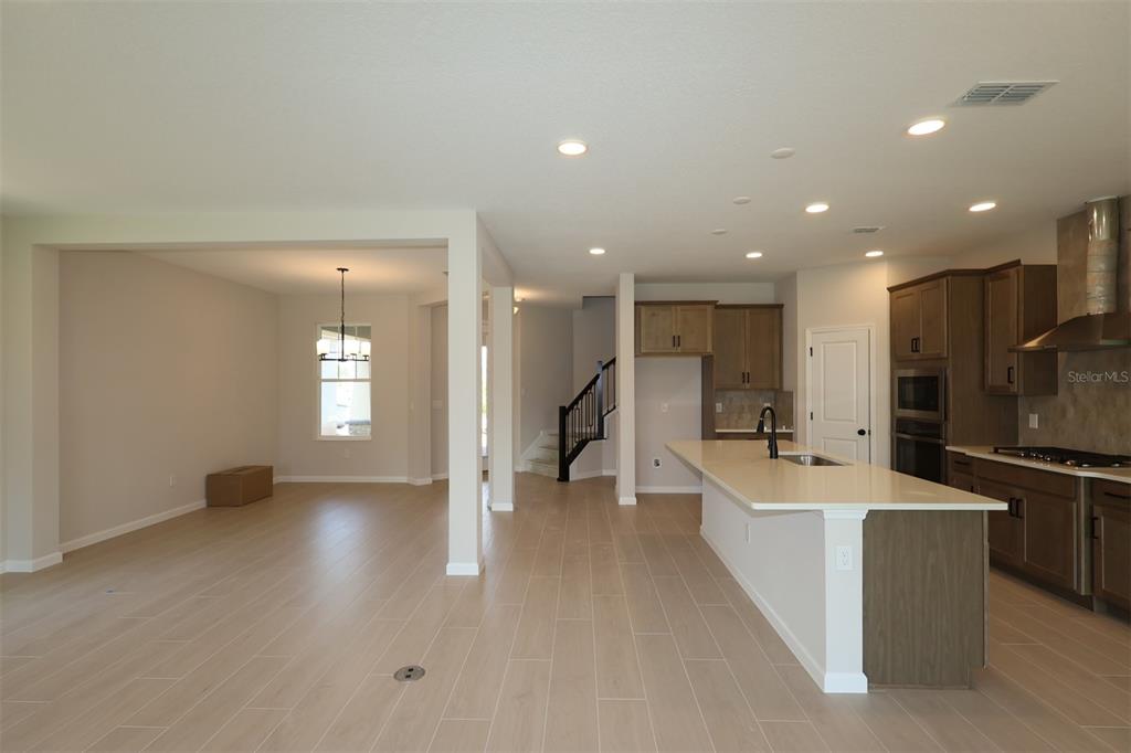 A modern kitchen with a large island and light wood-look tile flooring — 1314 HYDE STREET, ST CLOUD, FL