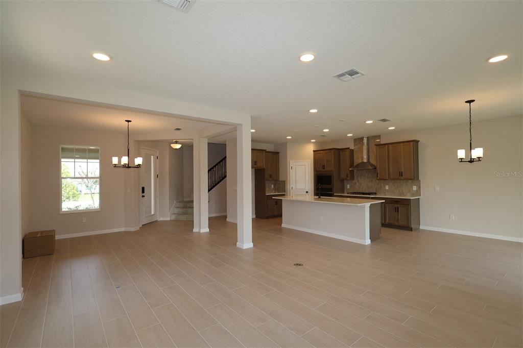 An open-concept kitchen and living area feature light wood-look tile flooring and recessed lighting — 1314 HYDE STREET, ST CLOUD, FL