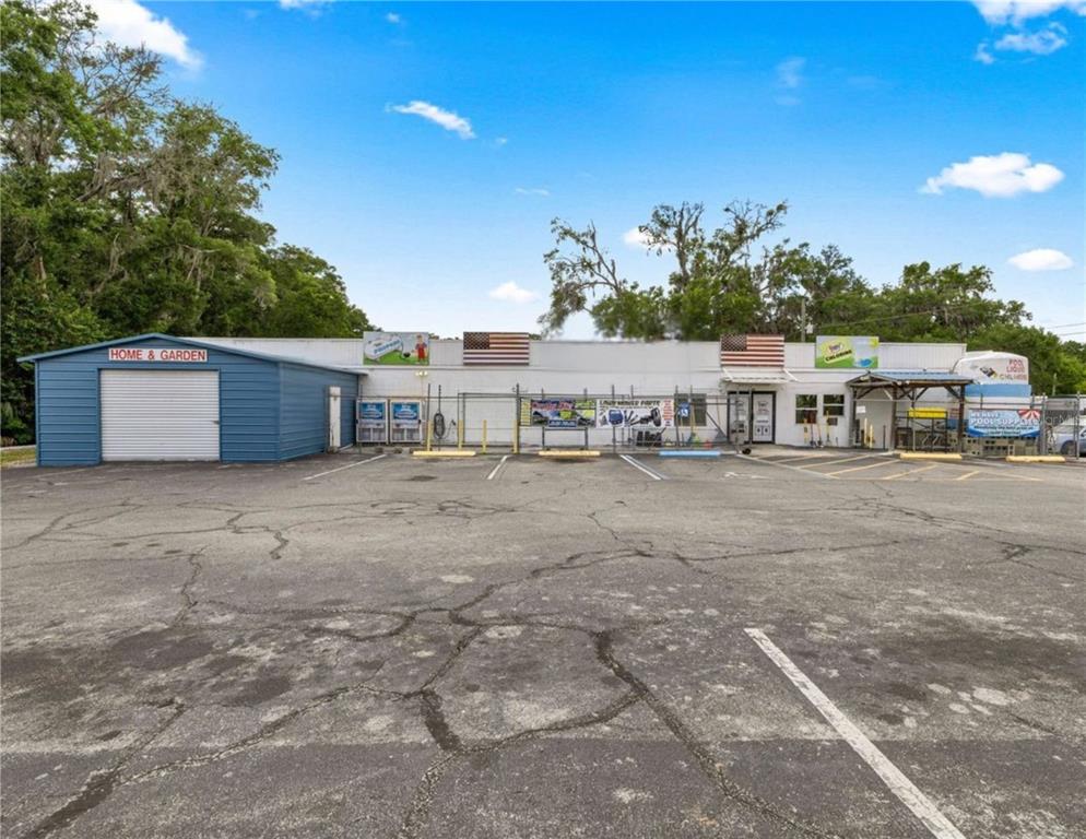 A commercial building with a blue garage, a parking lot, and American flags on the facade — 2926/3010 NE JACKSONVILLE ROAD, OCALA, FL
