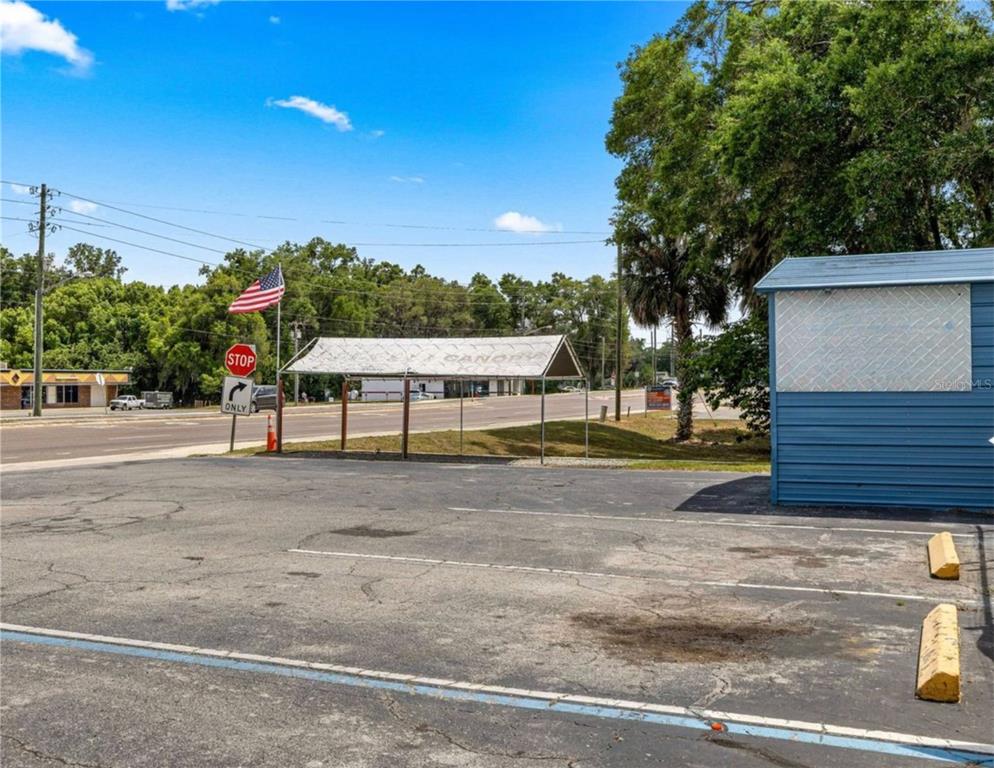 An outdoor parking lot features a metal canopy, a stop sign, and a blue building — 2926/3010 NE JACKSONVILLE ROAD, OCALA, FL