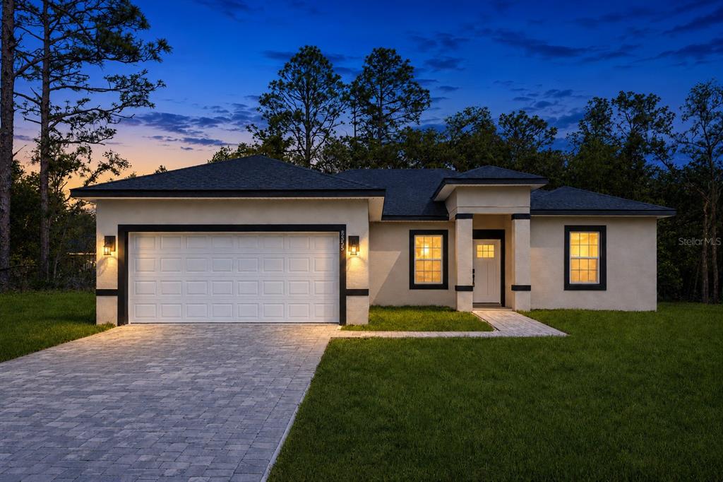 A single-story house with a white stucco exterior, black trim, and a paved driveway at dusk — 1978 W RUTLAND DRIVE, CITRUS SPRINGS, FL