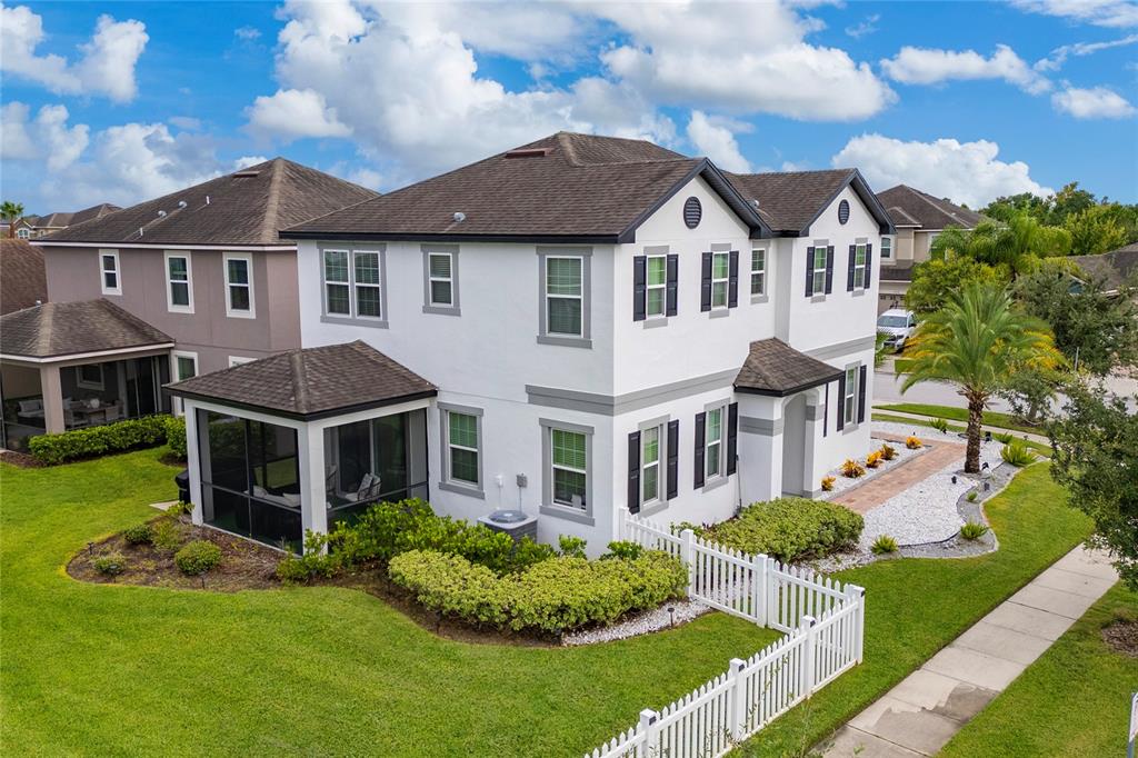 An aerial view of a two-story white house with a screened-in porch and white fence — 2527 NOUVEAU WAY, KISSIMMEE, FL