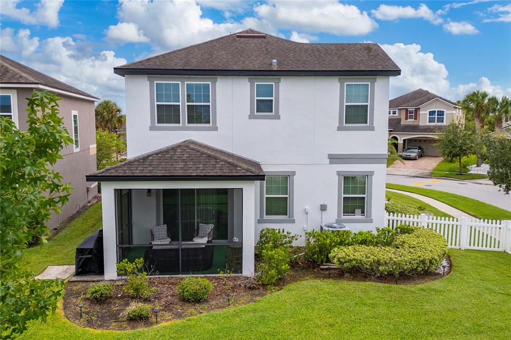 The rear exterior of a two-story white house features a screened-in patio and fenced yard — 2527 NOUVEAU WAY, KISSIMMEE, FL