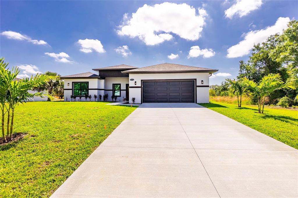 A modern single-story house with a dark garage door and a concrete driveway — 7316 DONAHUE STREET, PORT CHARLOTTE, FL