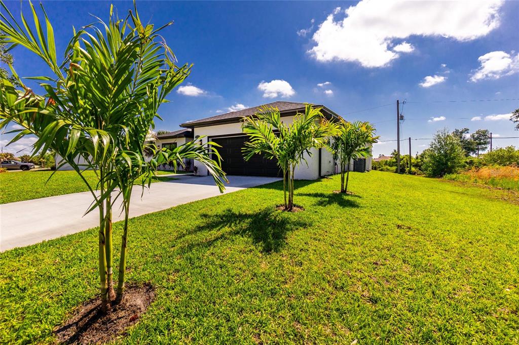 A single-story house with a dark garage door and palm trees in the front yard — 7316 DONAHUE STREET, PORT CHARLOTTE, FL