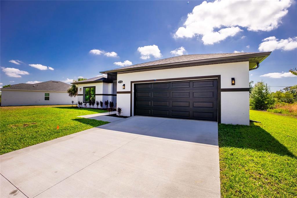 A modern single-story house with a white stucco exterior and a black two-car garage — 7316 DONAHUE STREET, PORT CHARLOTTE, FL