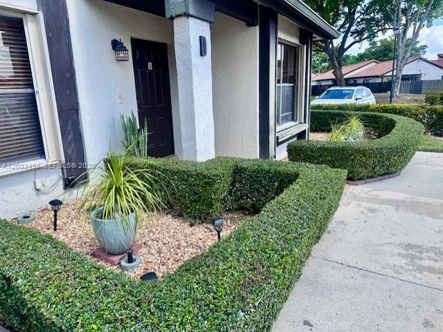 A front view of a house exterior featuring a manicured hedge and a potted plant — 15070 SW 49th Ln # D106, Miami FL 33185, MIAMI, FL