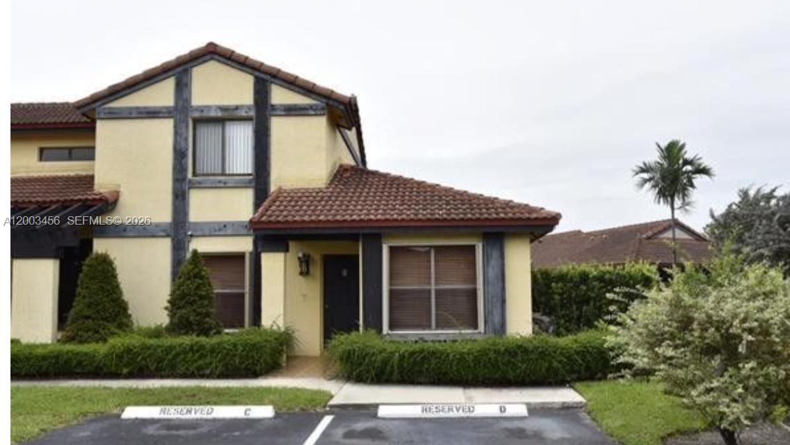 A two-story stucco townhouse with a tiled roof and two reserved parking spaces in front — 15070 SW 49th Ln # D106, Miami FL 33185, MIAMI, FL