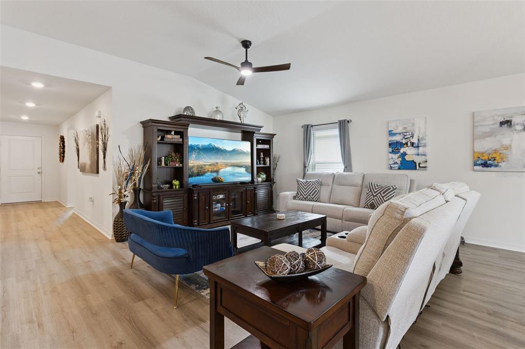 A living room features a dark wood entertainment center, light gray sofa, and blue accent chair — 3832 PRONGHORN DR, ST CLOUD, FL
