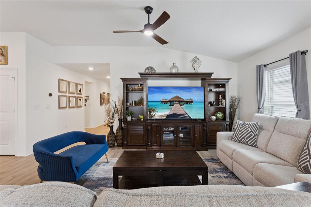 A living room features a dark wood entertainment center, a blue sofa, and a beige couch — 3832 PRONGHORN DR, ST CLOUD, FL