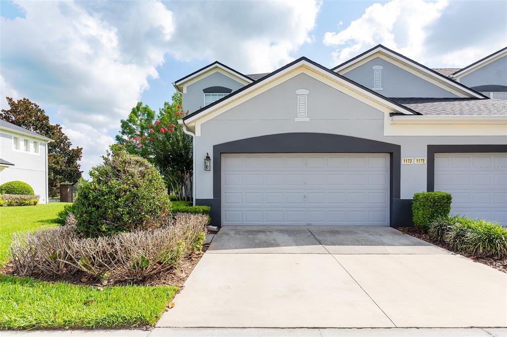 A gray two-story townhouse exterior features a two-car garage and a concrete driveway — 1173 SHALLCROSS AVENUE, ORLANDO, FL