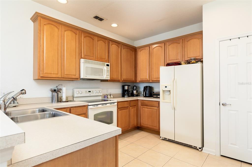 A kitchen features light wood cabinets, white appliances, beige countertops, and tile flooring — 1173 SHALLCROSS AVENUE, ORLANDO, FL