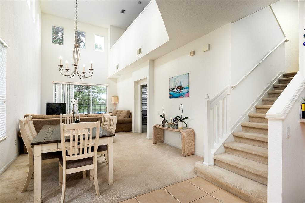 A dining area with a chandelier and staircase sits adjacent to a living room — 1173 SHALLCROSS AVENUE, ORLANDO, FL