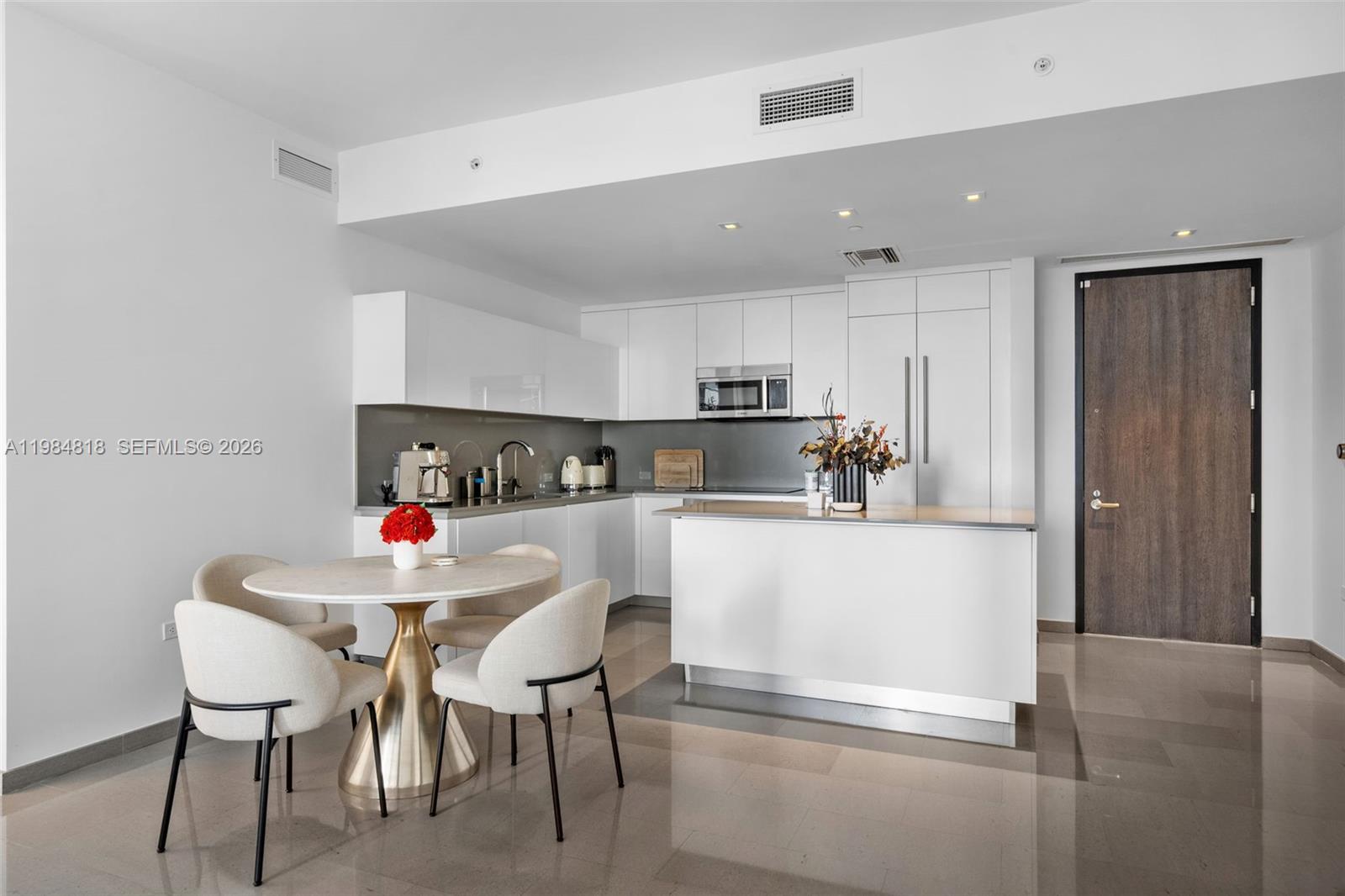 A modern kitchen features white cabinetry, a central island, and an adjacent circular dining table — 88 SW 7th St # 809, Miami FL 33130, MIAMI, FL