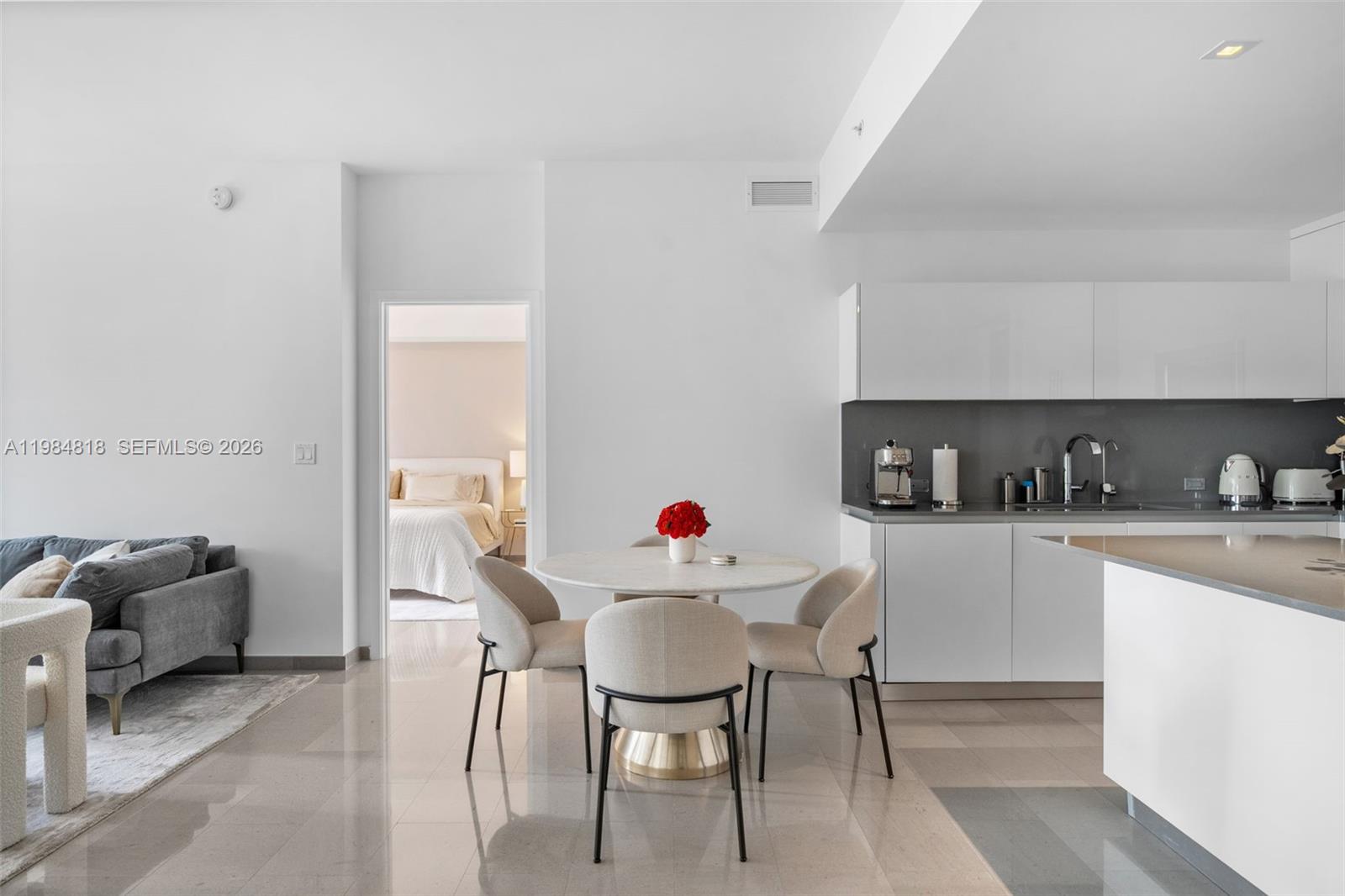 A modern open-plan kitchen and dining area features white cabinetry and a marble table — 88 SW 7th St # 809, Miami FL 33130, MIAMI, FL