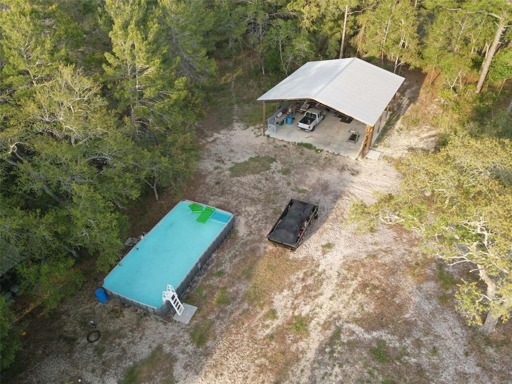 An aerial view shows a rectangular above-ground pool, a metal carport, and a utility trailer — 9172 QUIVIRA ROAD, BROOKSVILLE, FL