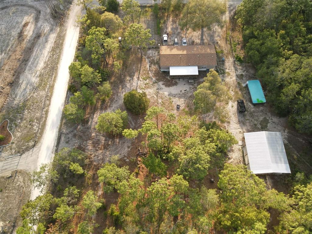 An aerial view shows a house with a pool and a detached garage on a wooded lot — 9172 QUIVIRA ROAD, BROOKSVILLE, FL