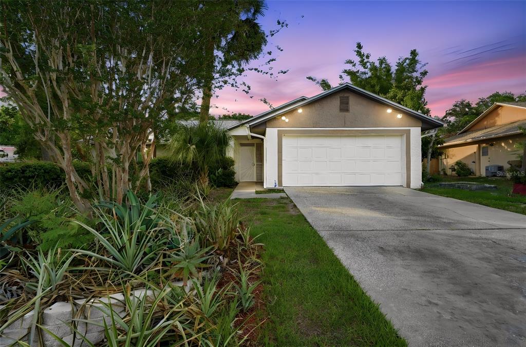 A single-story house with a white garage door, concrete driveway, and landscaped front yard — 8423 BERMUDA DUNES DRIVE, ORLANDO, FL