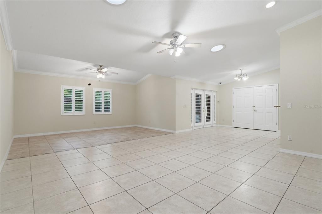 A spacious, light-filled living room features beige tile flooring, vaulted ceilings, and double glass doors — 8423 BERMUDA DUNES DRIVE, ORLANDO, FL