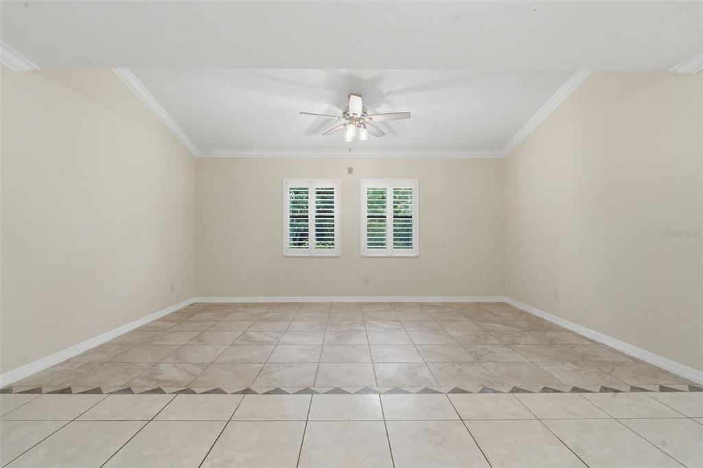 An empty room features beige walls, a tray ceiling with a fan, and tiled floors — 8423 BERMUDA DUNES DRIVE, ORLANDO, FL