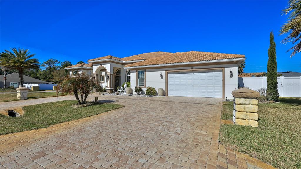 A single-story house with a white stucco exterior, tile roof, and a paved driveway — 1 ROCKWELL LANE, PALM COAST, FL
