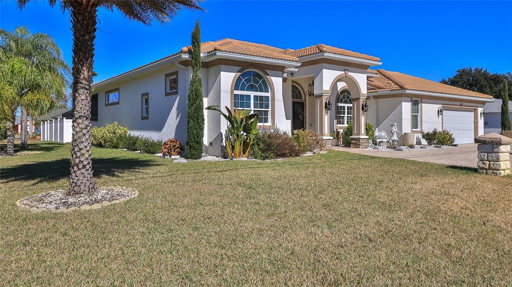 A single-story stucco house with a tile roof, arched windows, and a paved driveway — 1 ROCKWELL LANE, PALM COAST, FL