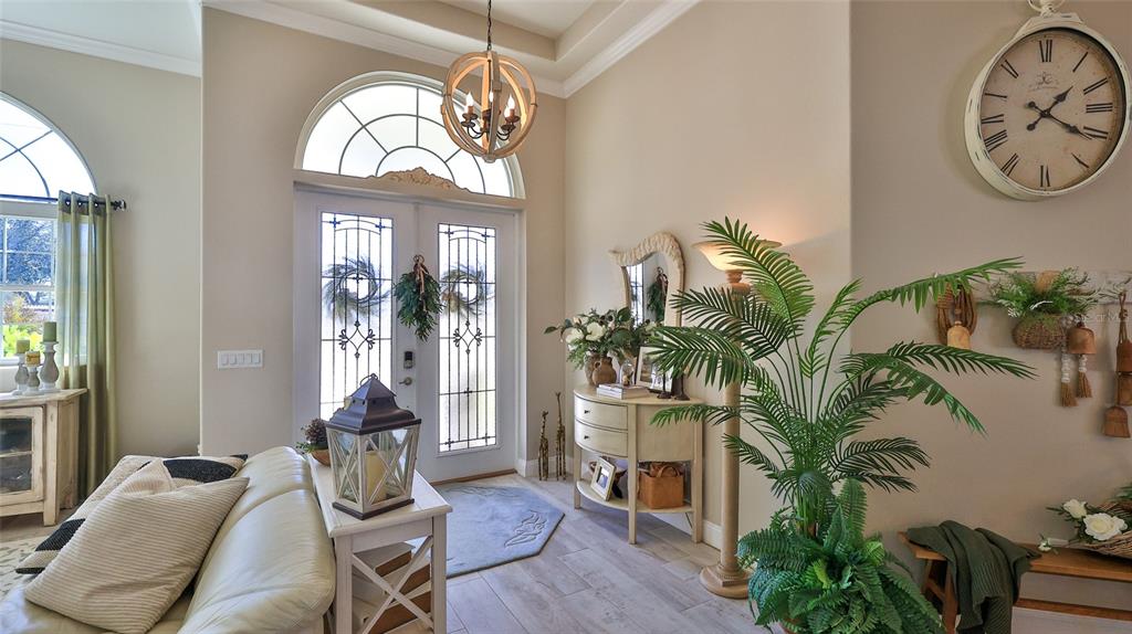 A bright entryway features a double front door, tile flooring, a chandelier, and a large clock — 1 ROCKWELL LANE, PALM COAST, FL