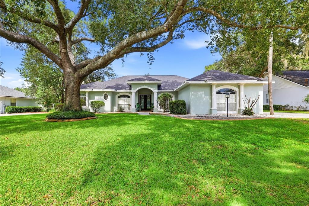 A single-story house with a large oak tree in the front yard — 6636 ROYAL FOREST DRIVE, LAKELAND, FL