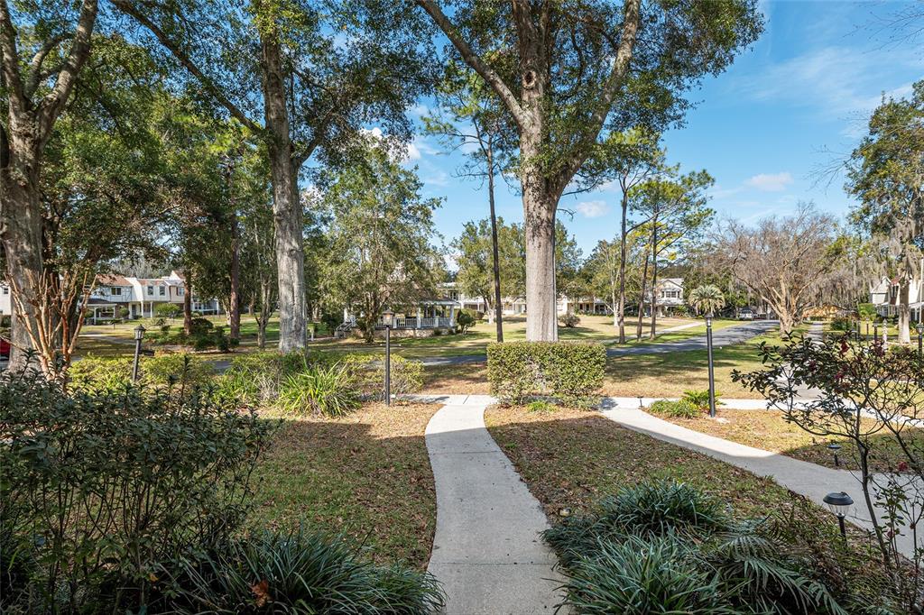 A concrete walkway leads through a grassy yard toward a gazebo and surrounding houses — 9951 SW 88TH COURT ROAD UNIT C, OCALA, FL