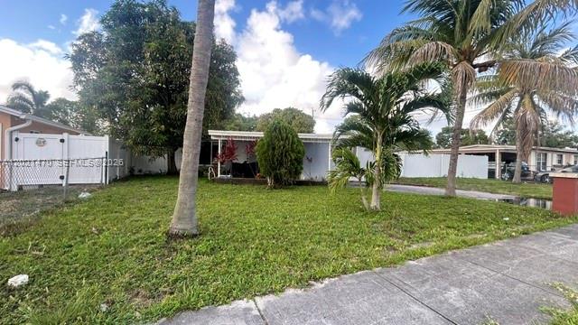 A single-story house with a lawn, palm trees, and a white fence under a blue sky — 3235 NW 2nd St, Lauderhill FL 33311, LAUDERHILL, FL