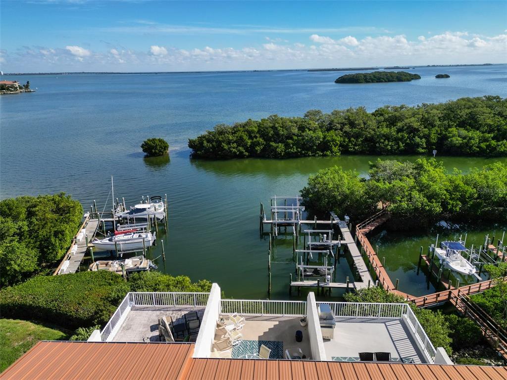 An elevated view of a waterfront deck overlooking boat docks, mangroves, and the open bay — 1593 PINELLAS BAYWAY S, TIERRA VERDE, FL