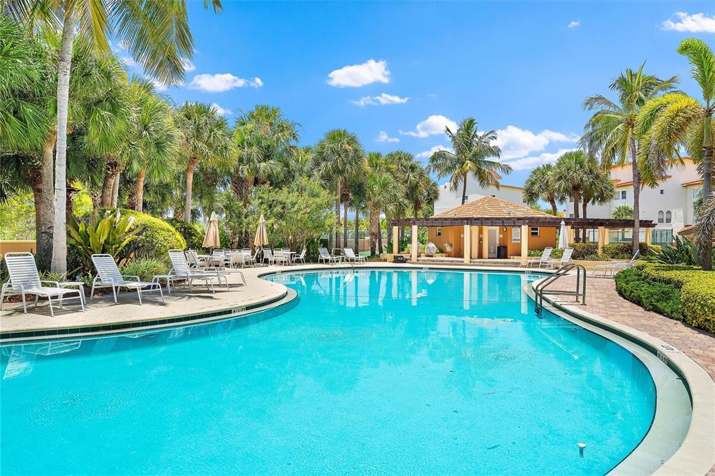 A swimming pool surrounded by lounge chairs, palm trees, and a covered patio area — 1593 PINELLAS BAYWAY S, TIERRA VERDE, FL