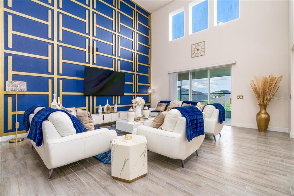 A living room features a tall blue and gold accent wall, white sofas, and tile flooring — 1296 WATERVIEW RIDGE CIRCLE, APOPKA, FL