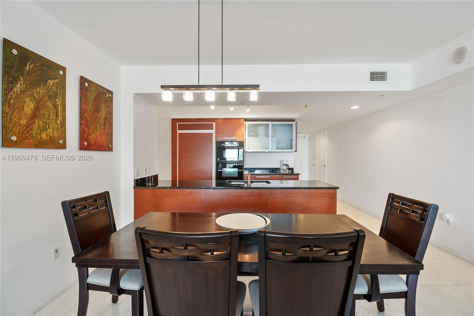 A dining area with a dark wood table and chairs sits before an open kitchen — 1830 S OCEAN DR # 3211, Hallandale Beach FL 33009, HALLANDALE BEACH, FL